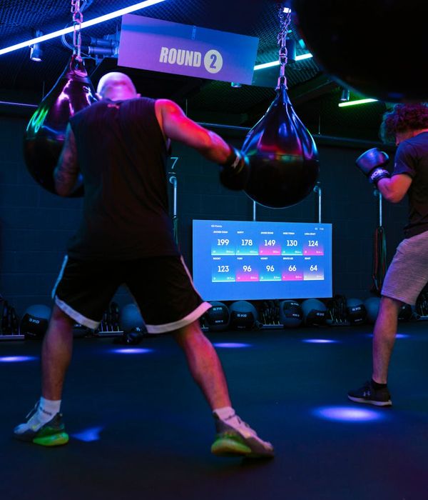 A man in his 40s performing a controlled strength exercise in a dark, modern gym.
